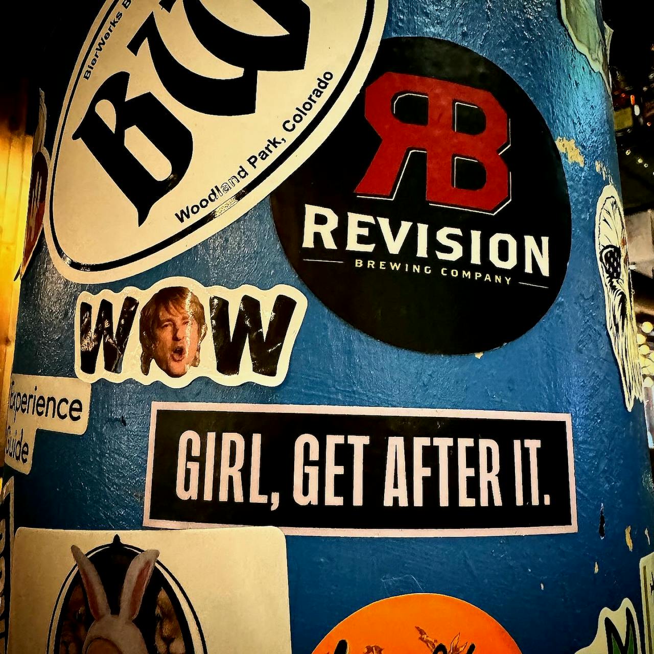 Stickers on a pole at a restaurant in Colorado Springs, featuring one reading, "Girl, Get After It"