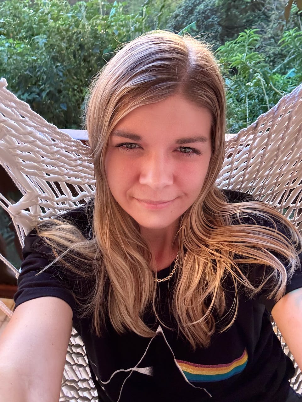 Selfie of Jade Pennig, smiling, sitting on a hammock in the jungle, wearing a Pink Floyd t-shirt