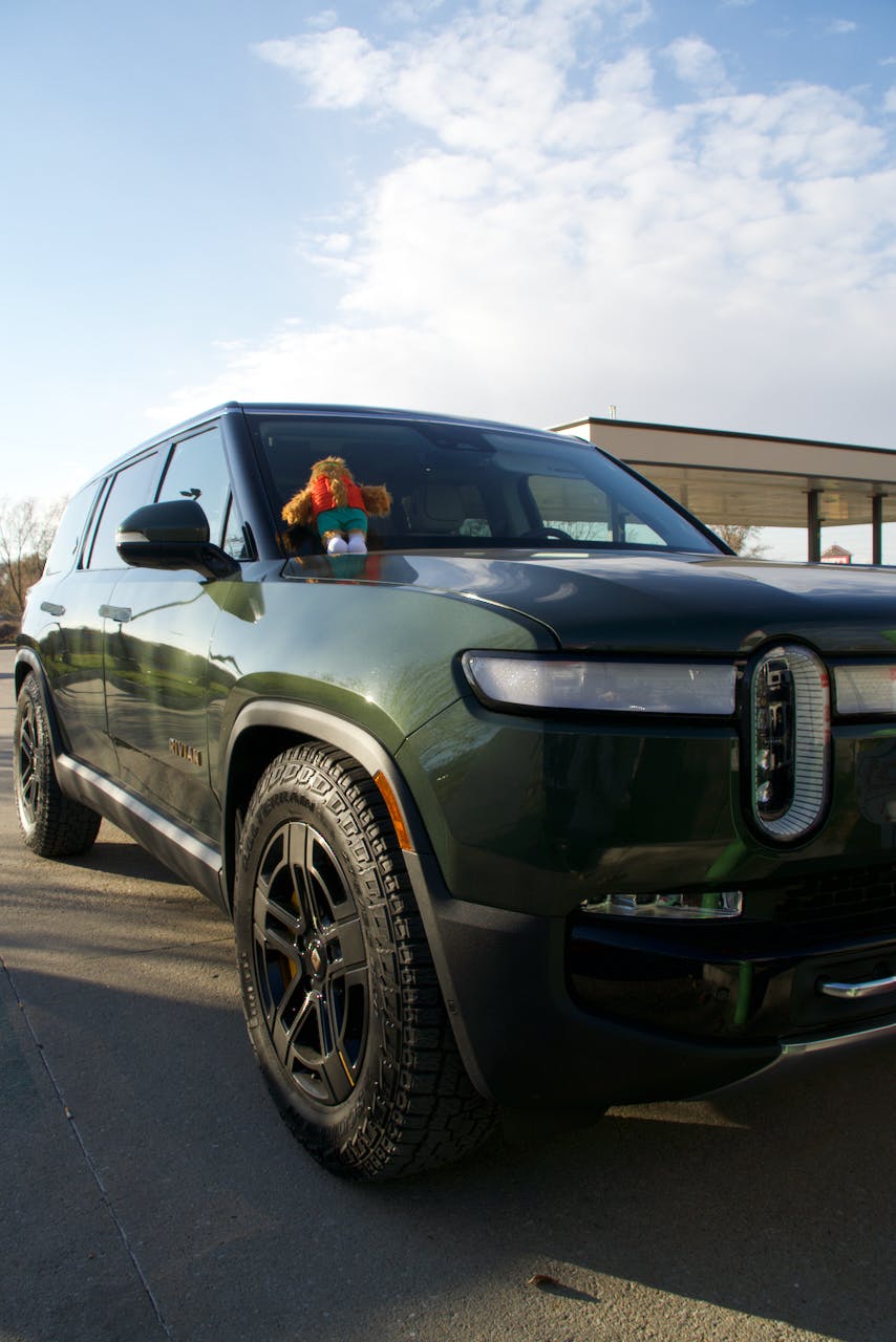 Gear Guard stuffie sitting on the windshield of a green Rivian R1S