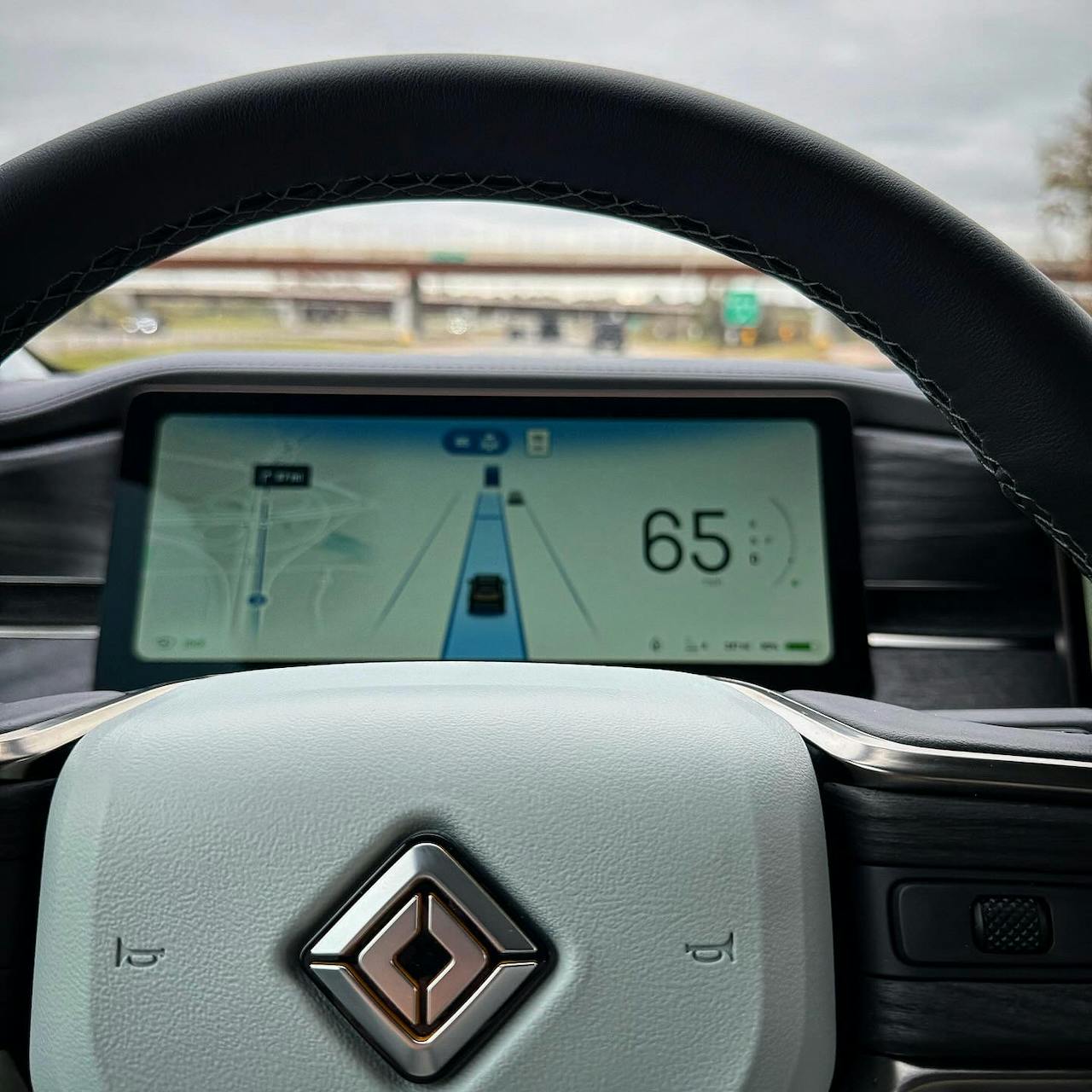 Rivian R1S dashboard showing the lane assist UI, driving at a speed of 65mph