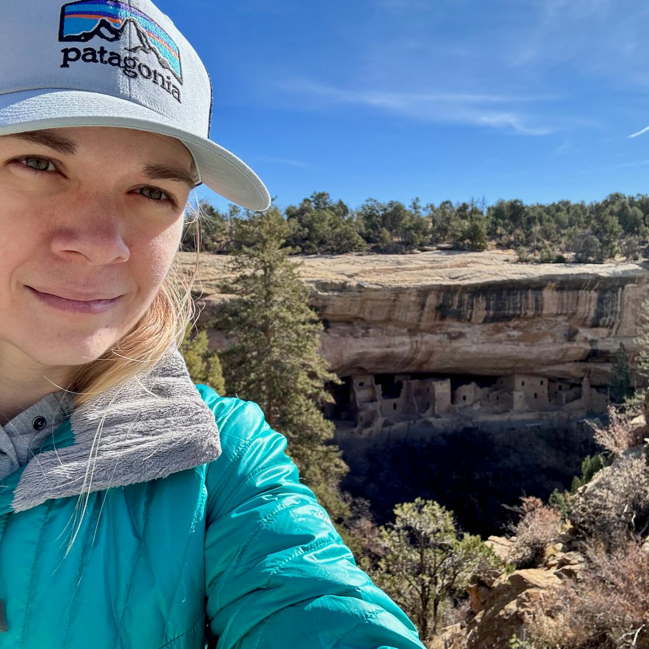 Selfie of Jade Pennig in front of Mesa Verde ruins, buildings which are carved into the side of a canyon in western Colorado